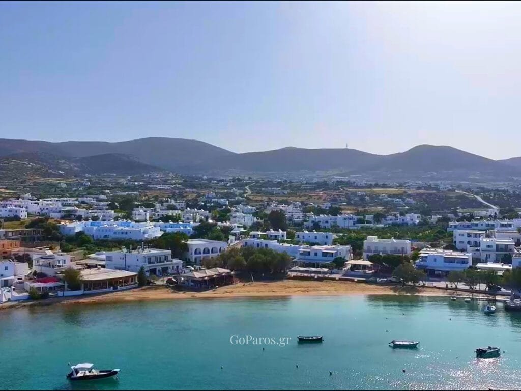 Aliki, Paros, aerial view of waterfront buildings beside a narrow sandy beach and turquoise sea