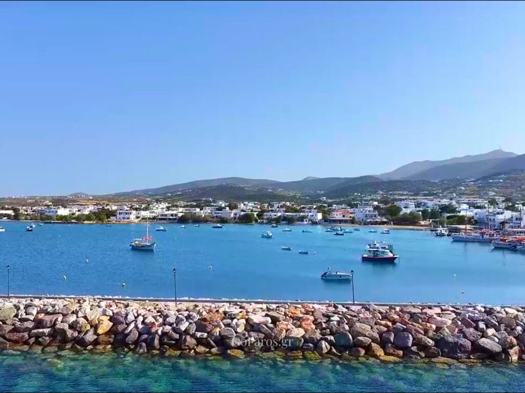 Aliki, Paros, view across the bay with small boats moored inside the harbor and a rock breakwater in the foreground