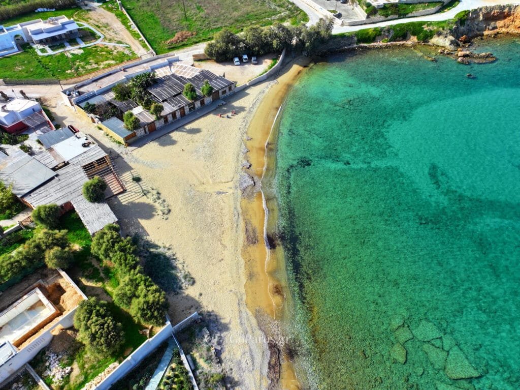 Delfini Beach, Paros, top-down aerial of the sandy beach and beachfront buildings beside clear water