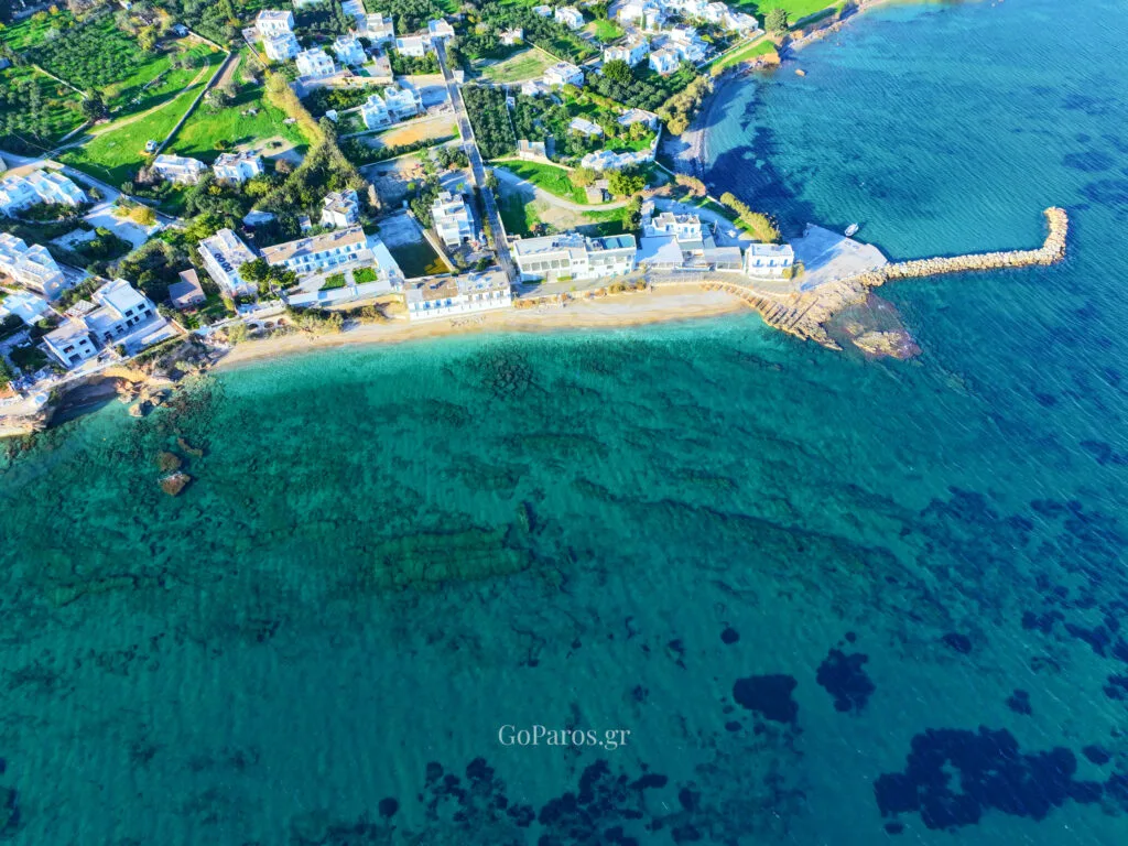 High aerial view of the bay by Drios Beach with shallow turquoise water and seaside buildings, Paros.