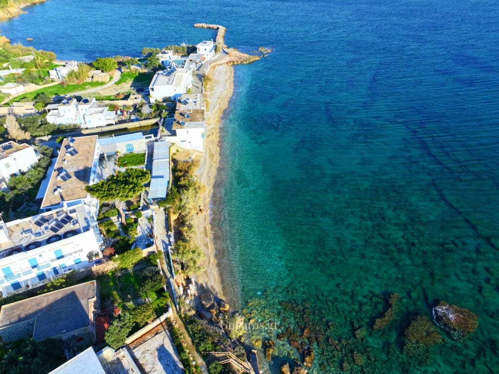 Aerial view of the Drios coastline with turquoise shallows and a small breakwater, Paros.