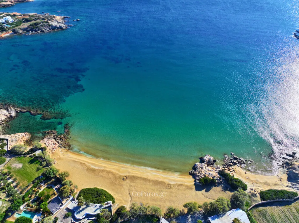 Drone view of Faraggas Beach in Paros with a curved sandy bay and clear blue water.