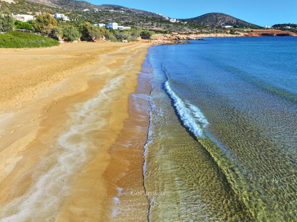 Aerial view near Faraggas Beach, Paros, with a rocky headland, fields inland, and deep blue sea.