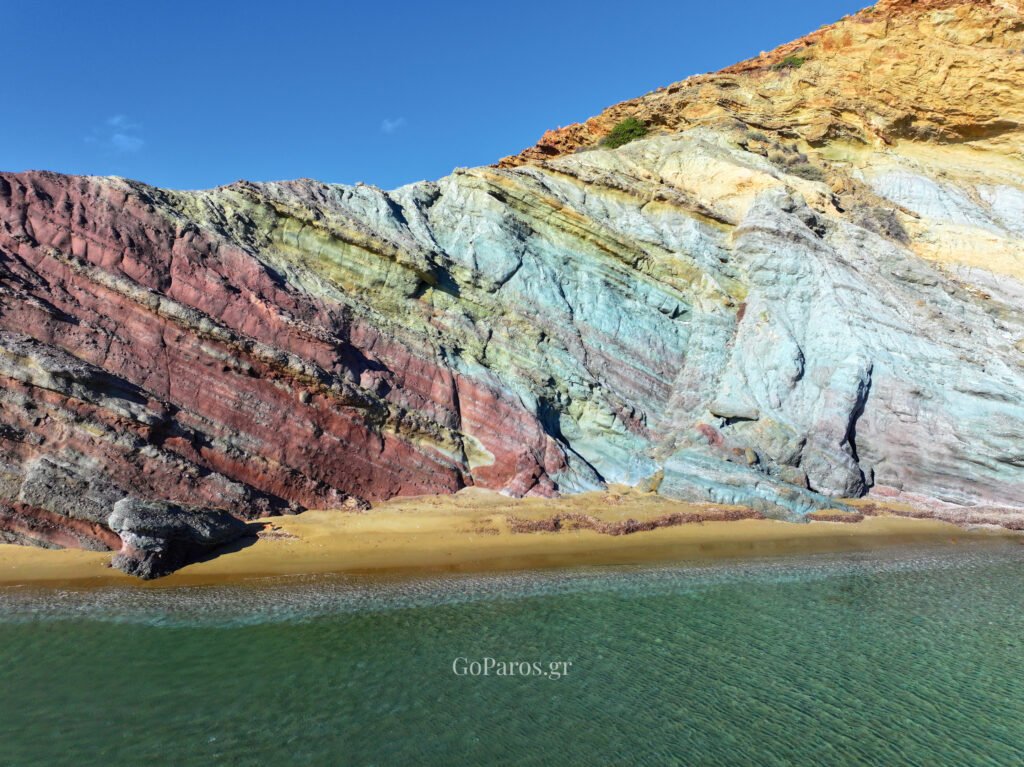 Layered, multicolored clay cliffs above the sand at Kalogeros Beach, Paros.