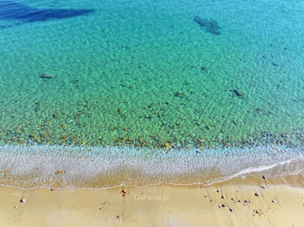 Clear shallow water and gentle waves along the shore at Kalogeros Beach, Paros.