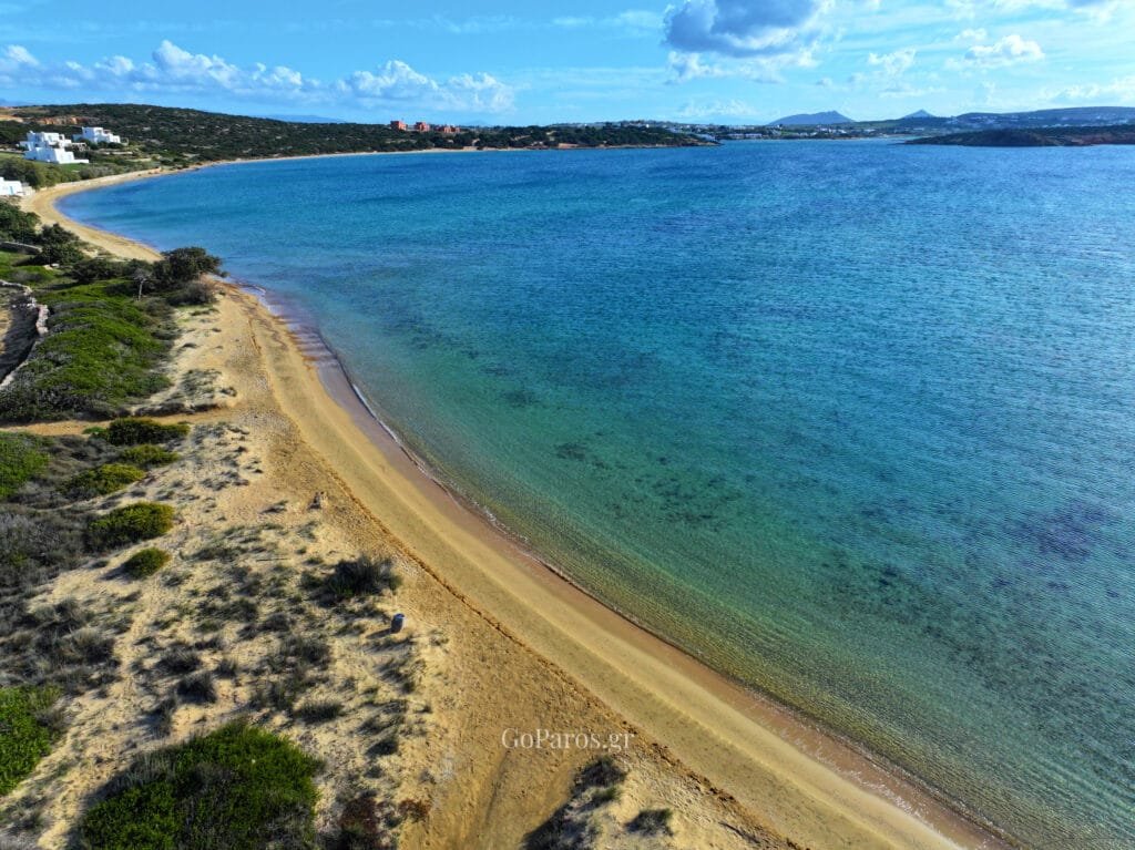 Laggeri Beach, Paros, aerial coastline view with a pier, clear water, and distant hills across the bay.