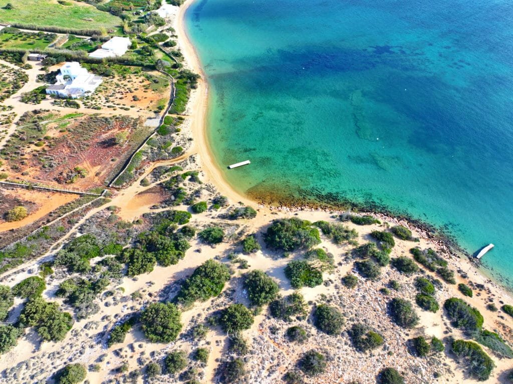 Laggeri Beach, Paros, aerial view of a sandy cove with clear turquoise water and rocky edges.