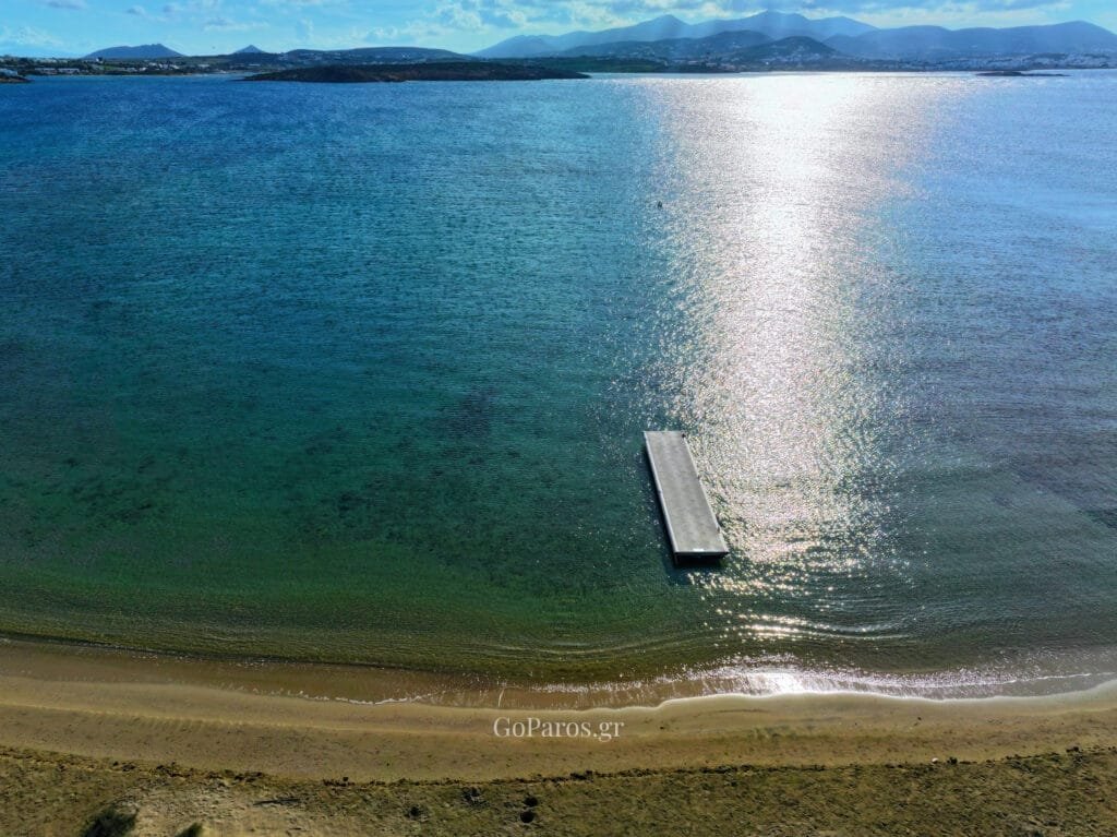 Laggeri Beach, Paros, wide sandy beach with calm water, low dunes, and coastal vegetation.