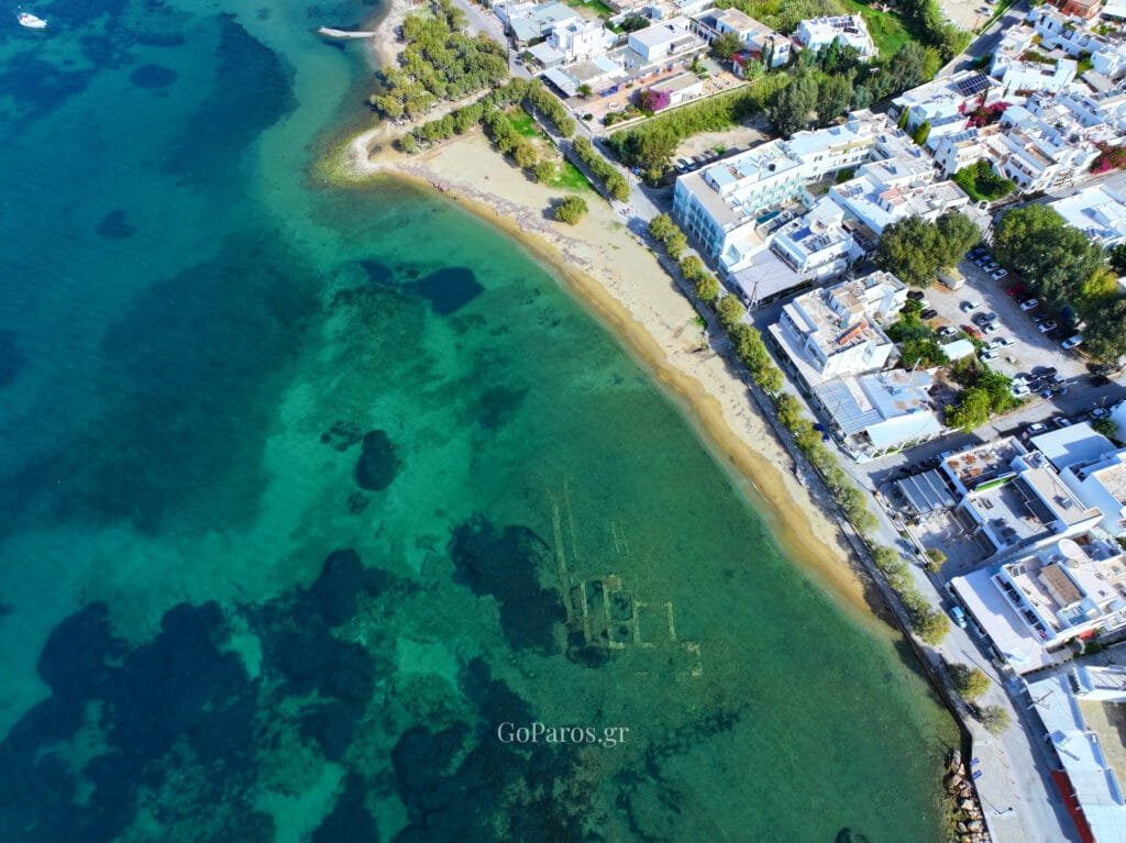 Livadia Beach, Paros, aerial view of the shallow turquoise shoreline beside the beachfront road and buildings