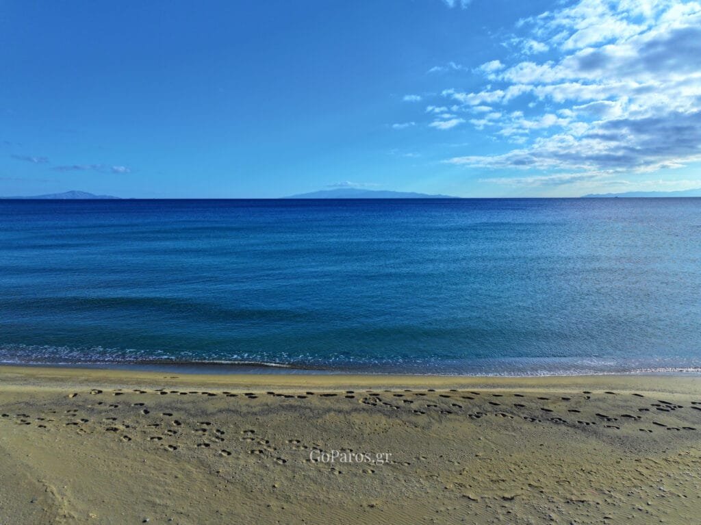 Calm Aegean Sea view from Lolantonis Beach, Paros, with soft sand and gentle waves.