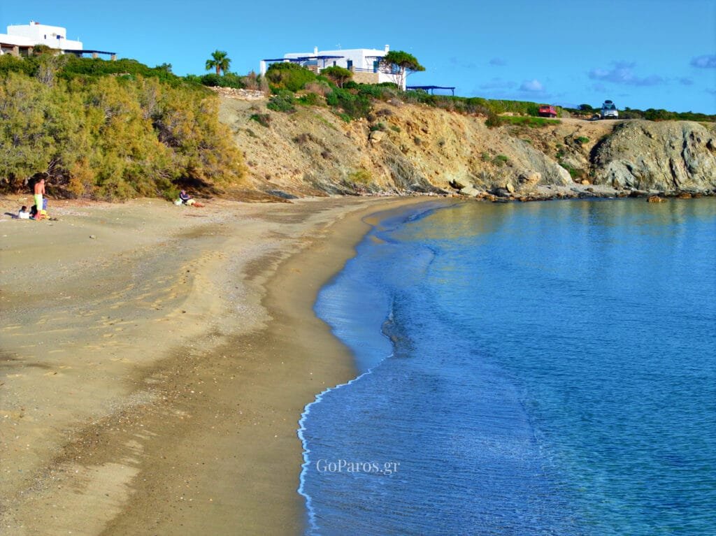 Small sheltered cove at Lolantonis Beach, Paros, with rocky backdrop and a few beachgoers.