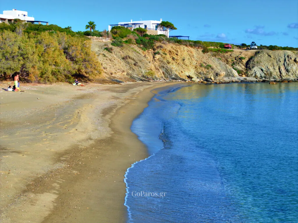 Small sheltered cove at Lolantonis Beach, Paros, with rocky backdrop and a few beachgoers.