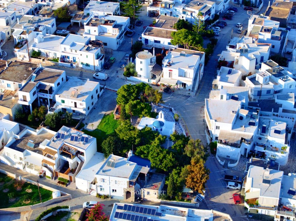 Marmara, Paros, aerial view of a village square with a small blue-domed chapel surrounded by pine trees and white houses