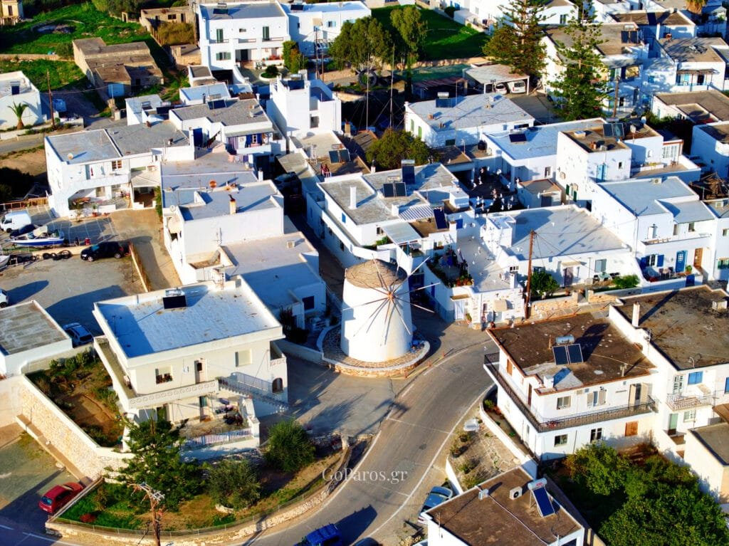 Marmara, Paros, aerial view of a village square with a small white washed mill surrounded by pigeons, pine trees and white houses