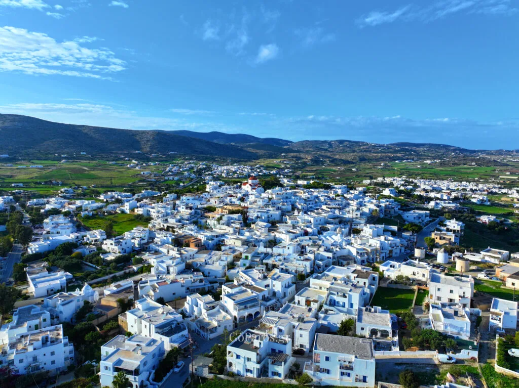 Marpissa, Paros, high aerial view of the whitewashed village spreading into surrounding fields under a wide blue sky