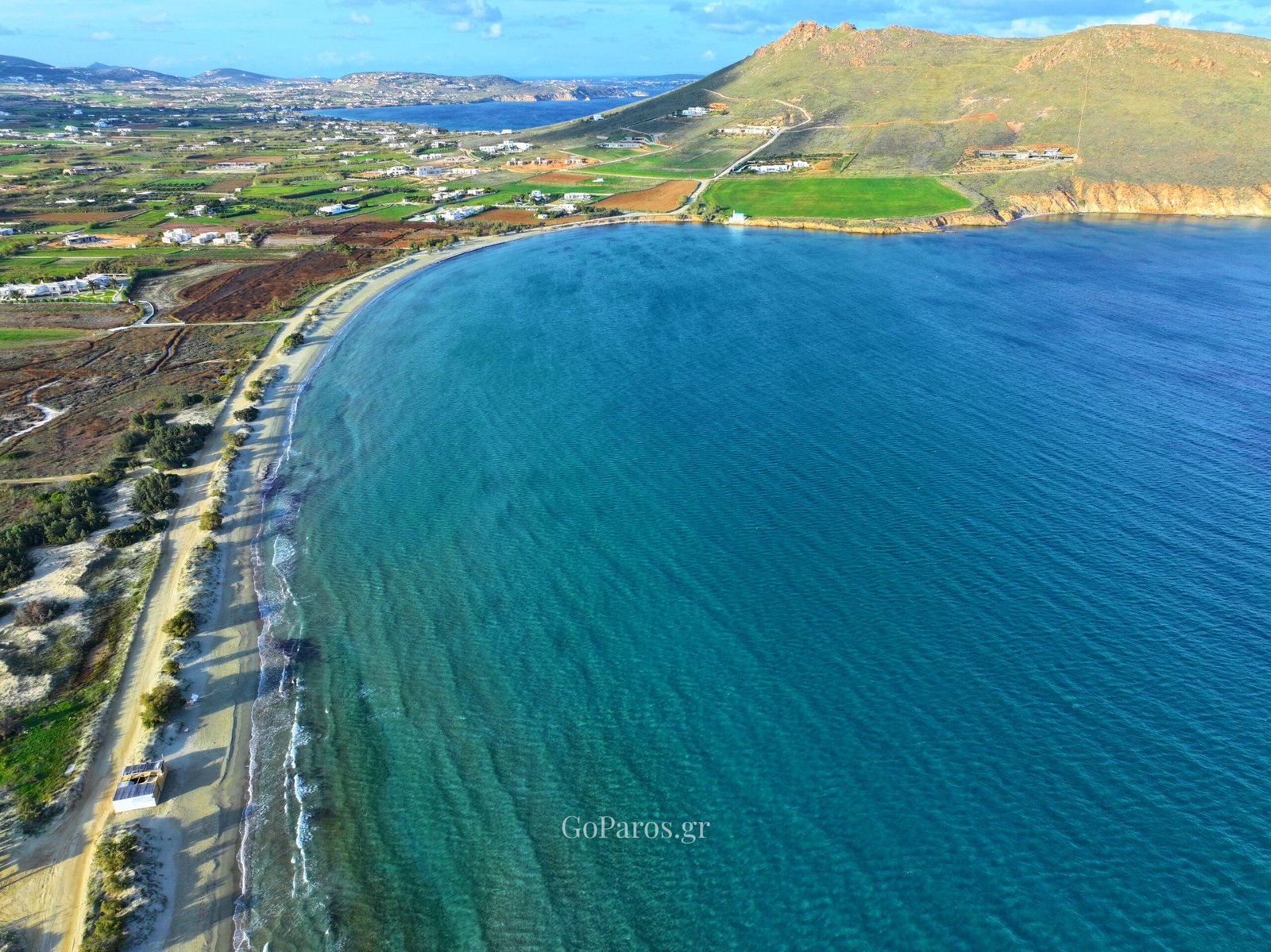 Curved bay and long shoreline at Molos Beach, Paros, from above.
