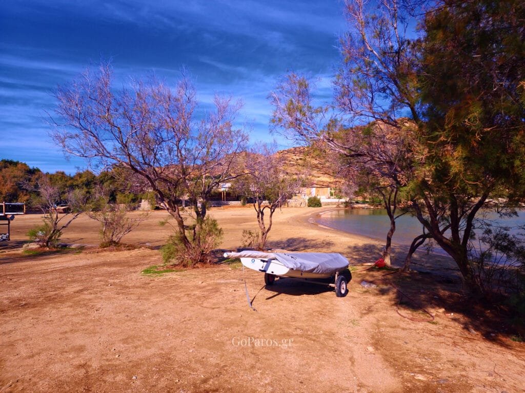 monastiri beach in paros, trees and a small boat on a trailer near the sand