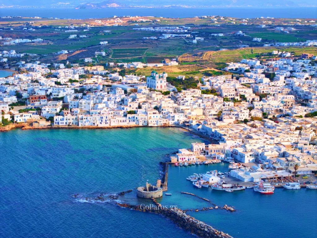 Naoussa, Paros, aerial view of the harbor and surrounding town with boats, turquoise water, and coastline