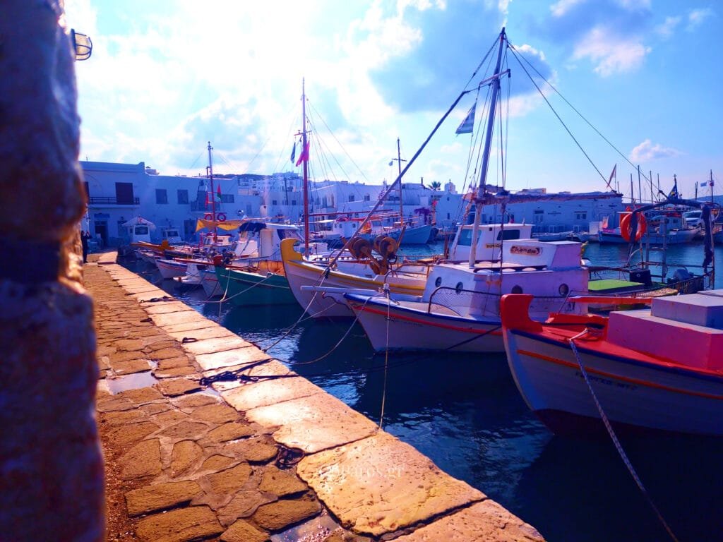 Naoussa, Paros, fishing boats tied along a stone quay with ropes and reflections in the harbor