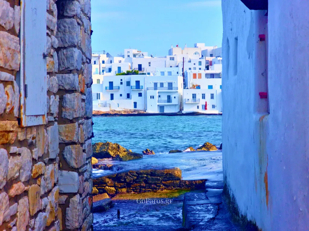 Naoussa, Paros, view through a narrow seaside passage to the water and white houses across the bay