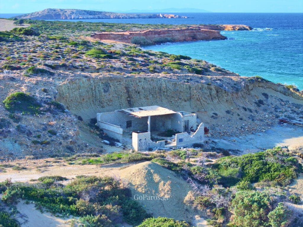Palio Karnagio Beach, Paros, abandoned concrete building in an eroded gully with sea and headland in the background