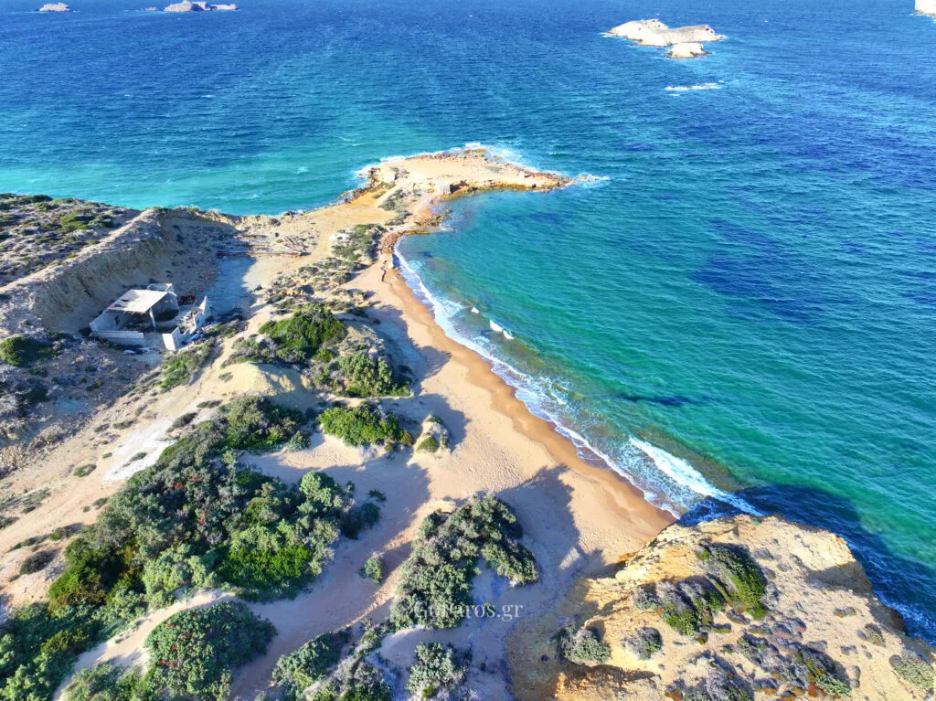 Palio Karnagio Beach, Paros, aerial view of sandy cove with eroded cliff, abandoned building, and clear green-blue water