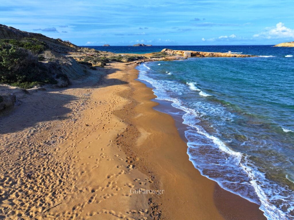 Palio Karnagio Beach, Paros, long beach perspective with gentle waves, sandy shore, and small islets on the horizon