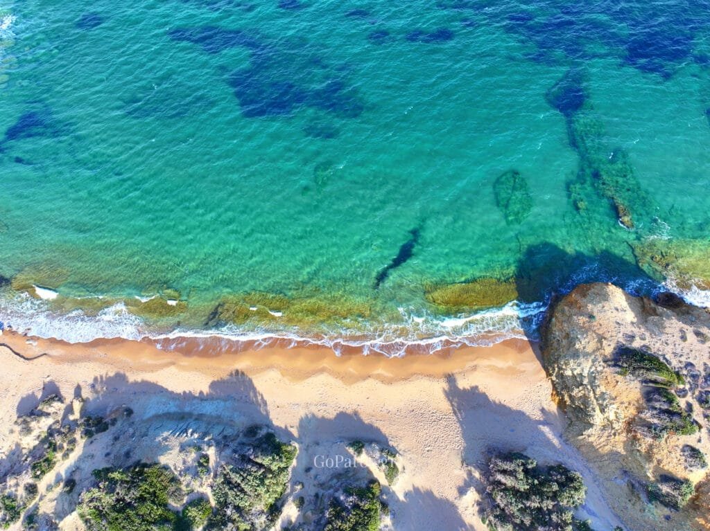 Palio Karnagio Beach, Paros, top-down aerial of narrow sand strip with clear turquoise water and rocky outcrop