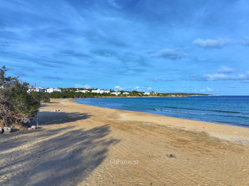 Wide view of a curved sandy beach and calm sea in Santa Maria beach, Paros
