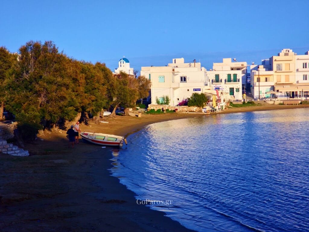 Piso Livadi Beach, Paros, shoreline with small boat and village with blue dome church.