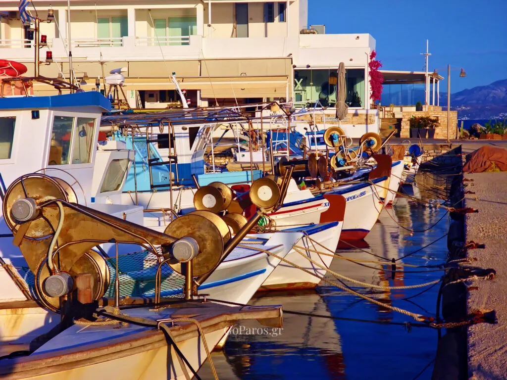 Piso Livadi, Paros, fishing boats moored along the harbor quay with winches and ropes in the foreground.