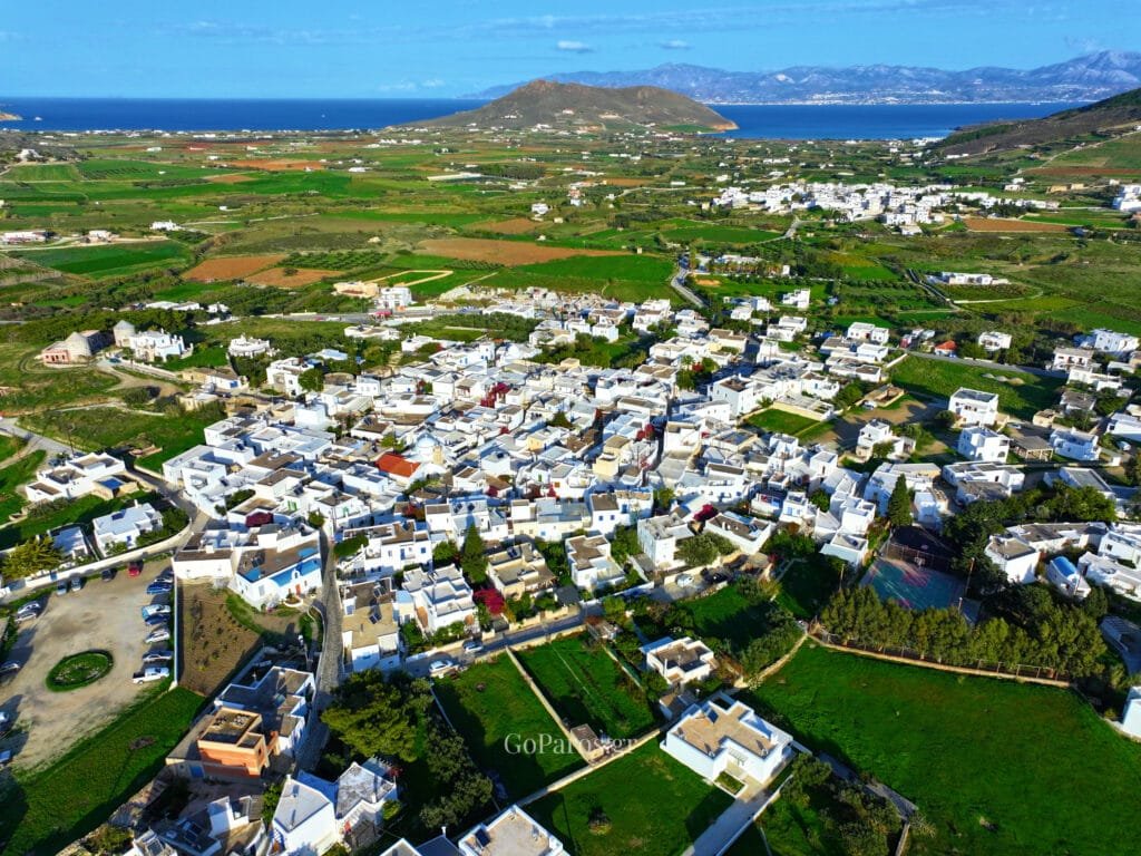 Prodromos, Paros, aerial view of the whitewashed village surrounded by green fields with the Aegean Sea and distant islands in the background