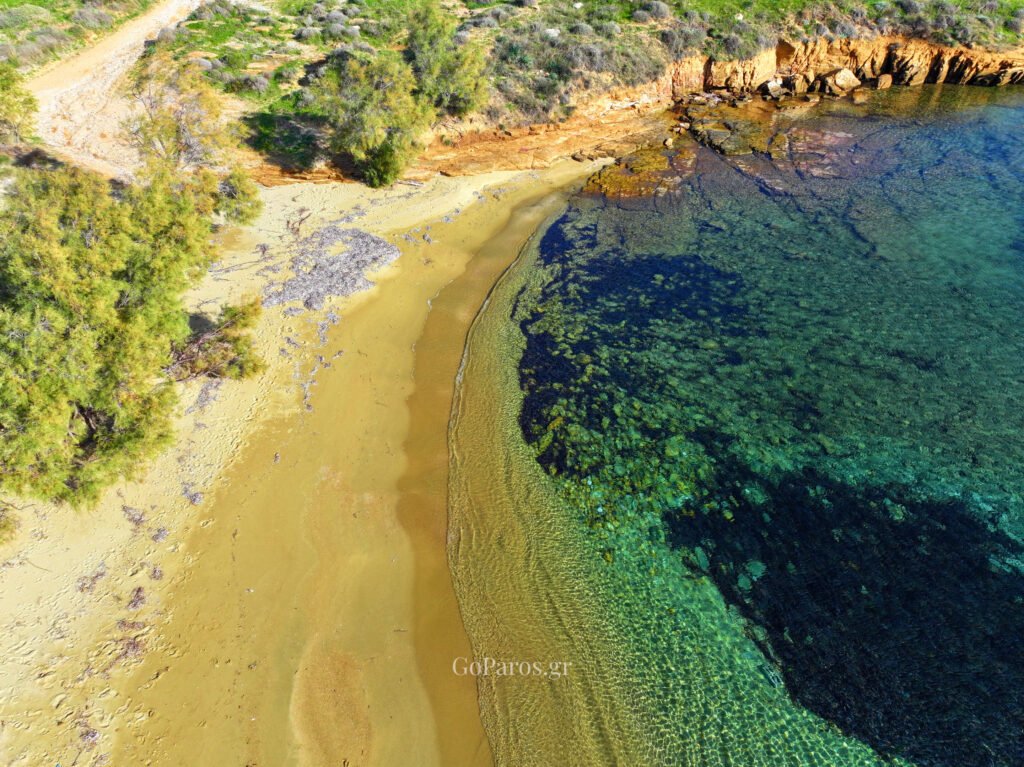 Aerial view of a small sandy cove with rocky seabed and clear water at Punda Beach East, Paros.