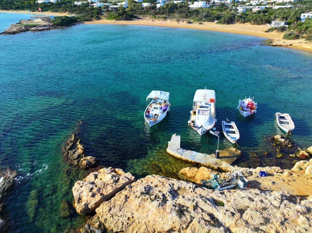 Small Santa Maria Beach, Paros, aerial view of the bay with a small pier and boats in turquoise water.