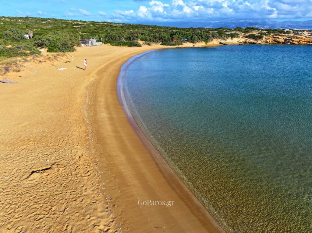 Small Santa Maria Beach, Paros, aerial view of a rocky peninsula and green fields meeting the sea.