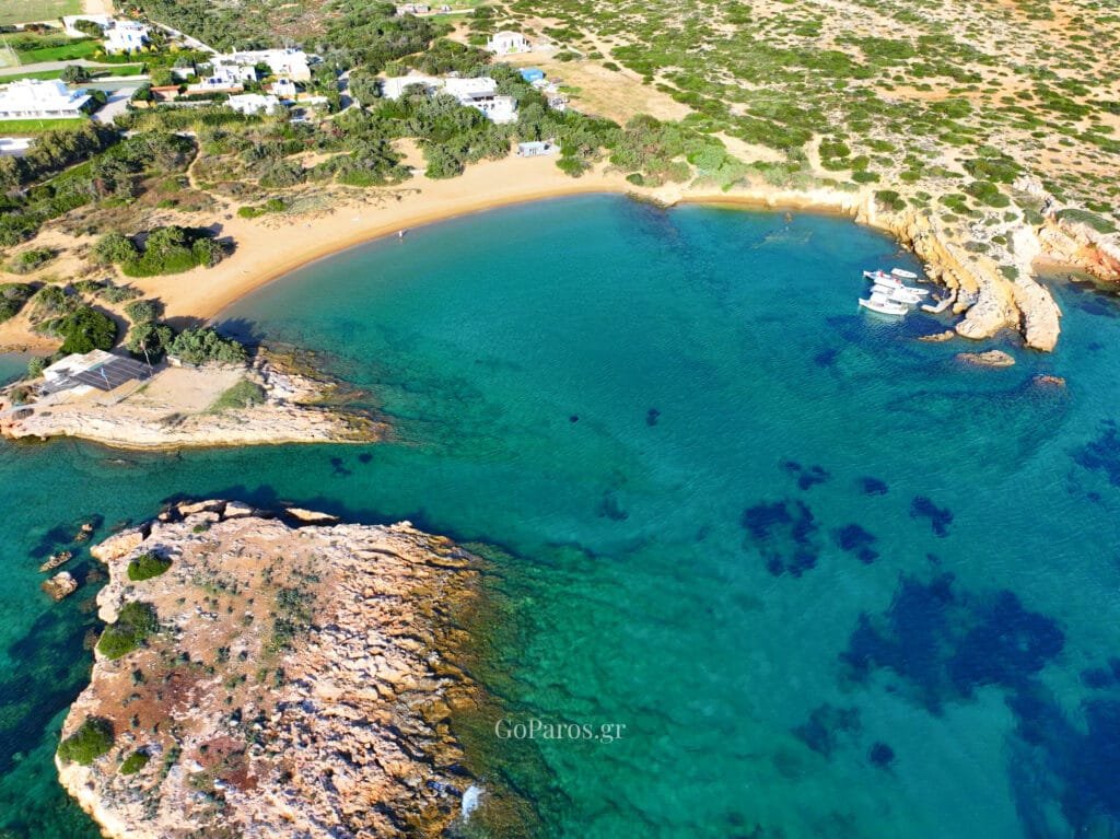 Small Santa Maria Beach, Paros, view across the bay with sandy beach, clear water, and hillside houses.