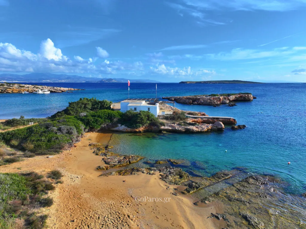 Small Santa Maria Beach, Paros, overhead view of a pebble beach and clear turquoise water beside a wooden walkway.