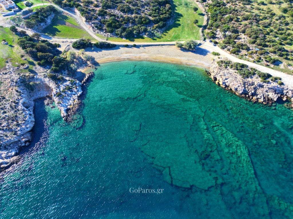 Drone photo of Tripiti Beach in Paros with the full bay, curved shoreline, and the access road behind the beach.