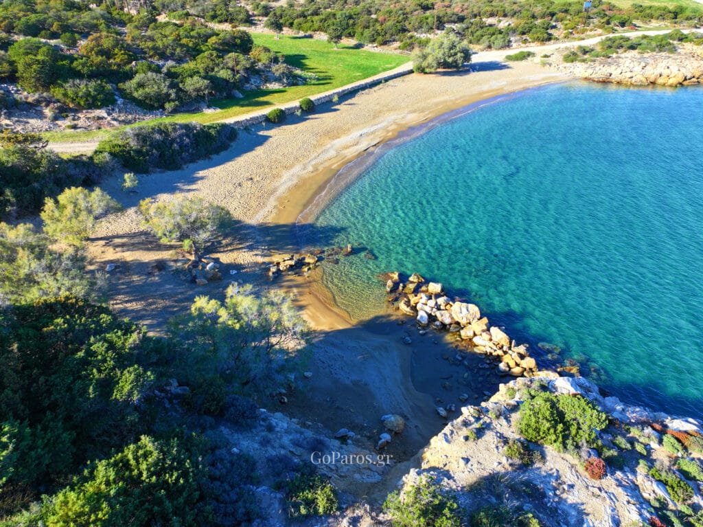Aerial view of Tripiti Beach, Paros, with a calm bay, clear water, and a curved sandy shoreline.
