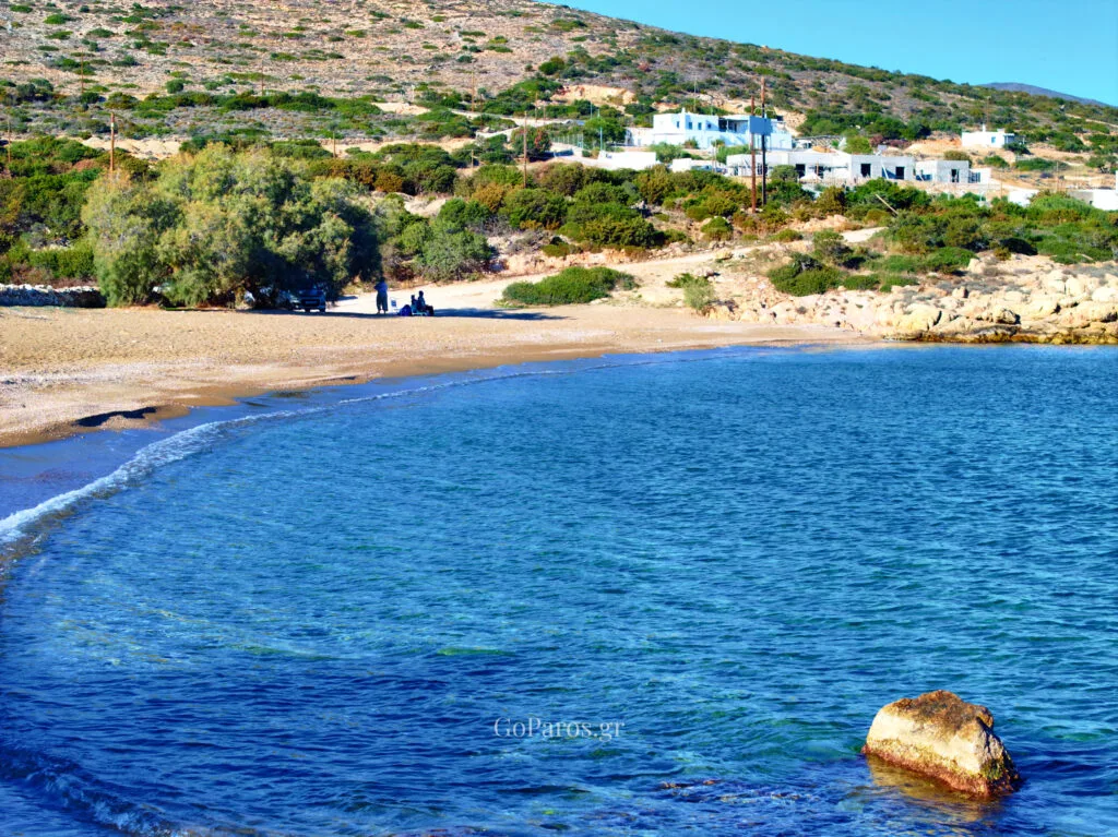 Calm water at Tripiti Beach, Paros, with a gentle shoreline and a rocky point in the distance.