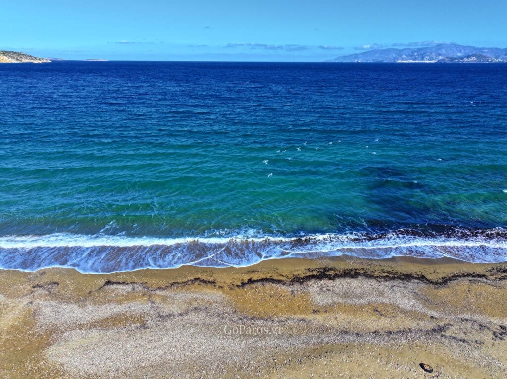 Small sandy cove at Tsoukalia Beach in Paros with calm, clear water and rocks.