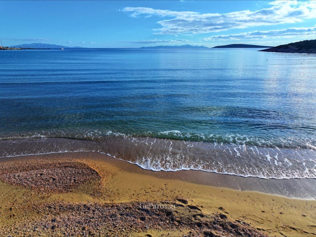 Agios Nikolaos Beach, Aliki, Paros, gentle wave on pebbly shore with islands on the horizon