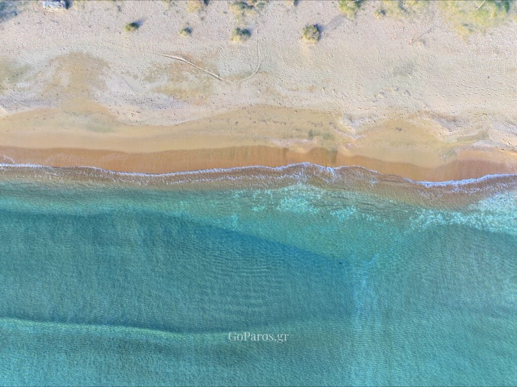 Agios Nikolaos Beach, Aliki, Paros, aerial view of sandy shoreline and shallow turquoise water at sunset