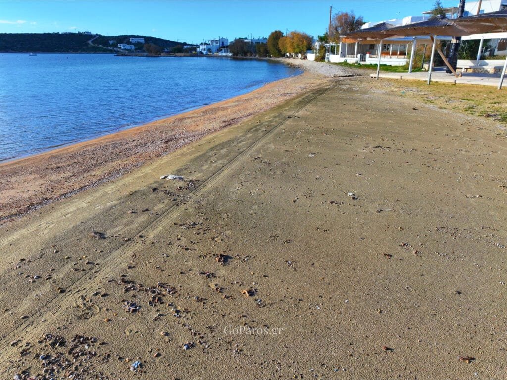 Aliki Beach, Paros, shoreline view with village buildings and calm bay water