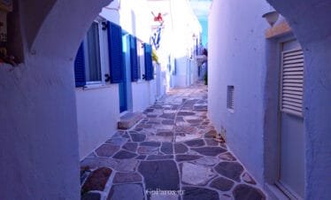Lefkes, Paros, traditional stone alley viewed through a white archway with blue shutters