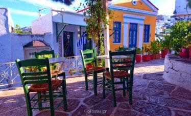 Lefkes, Paros, small cafe terrace with green chairs and colorful Cycladic buildings