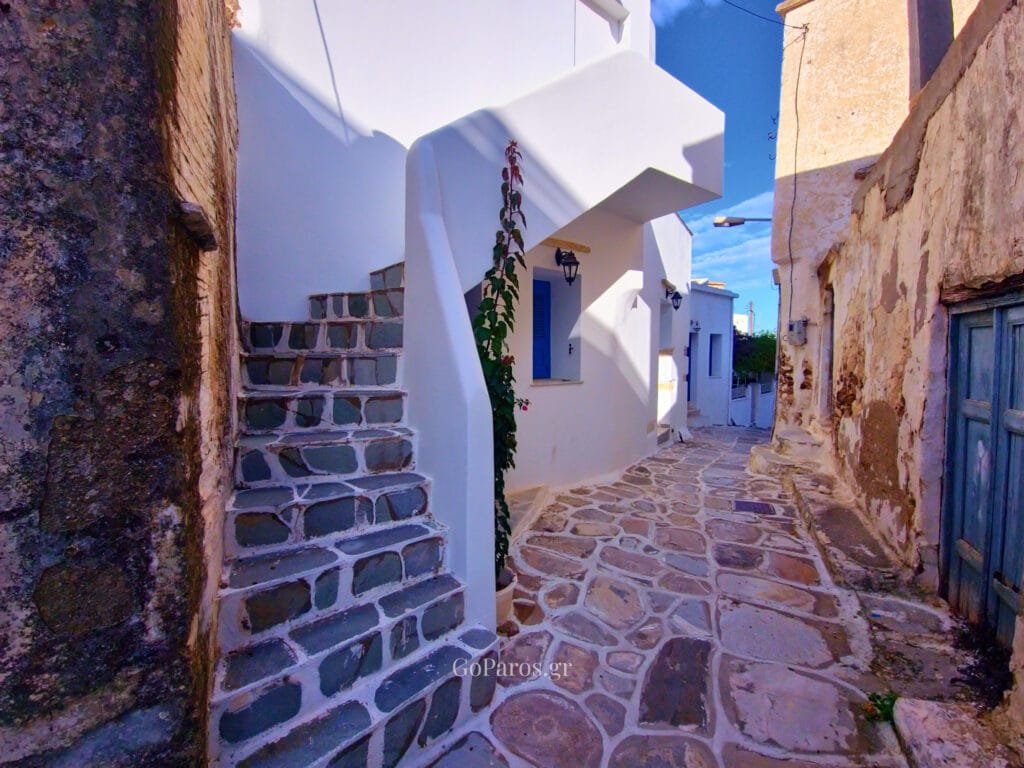 Lefkes, Paros, narrow village alley with stone paving, steps, and blue shutters