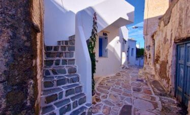 Lefkes, Paros, narrow village alley with stone paving, steps, and blue shutters