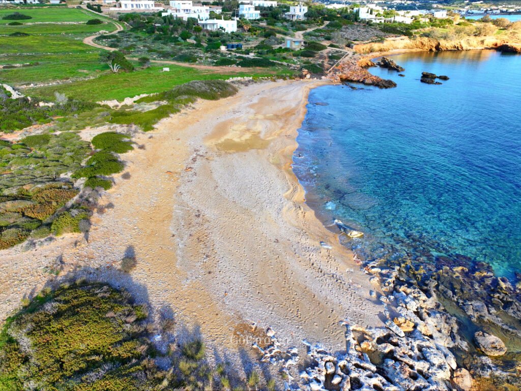 Makria Miti Beach, Paros, elevated view of the beach with coastal rocks, nearby houses, and clear water