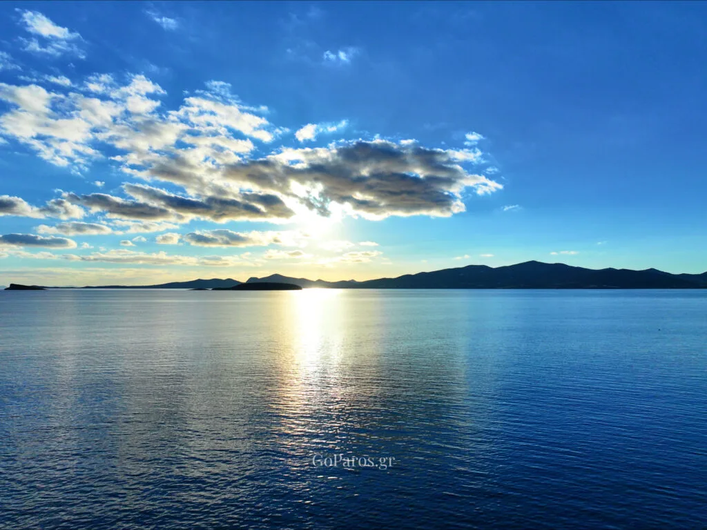 Makria Miti Beach, Paros, sunset light over calm sea with clouds and distant island silhouettes